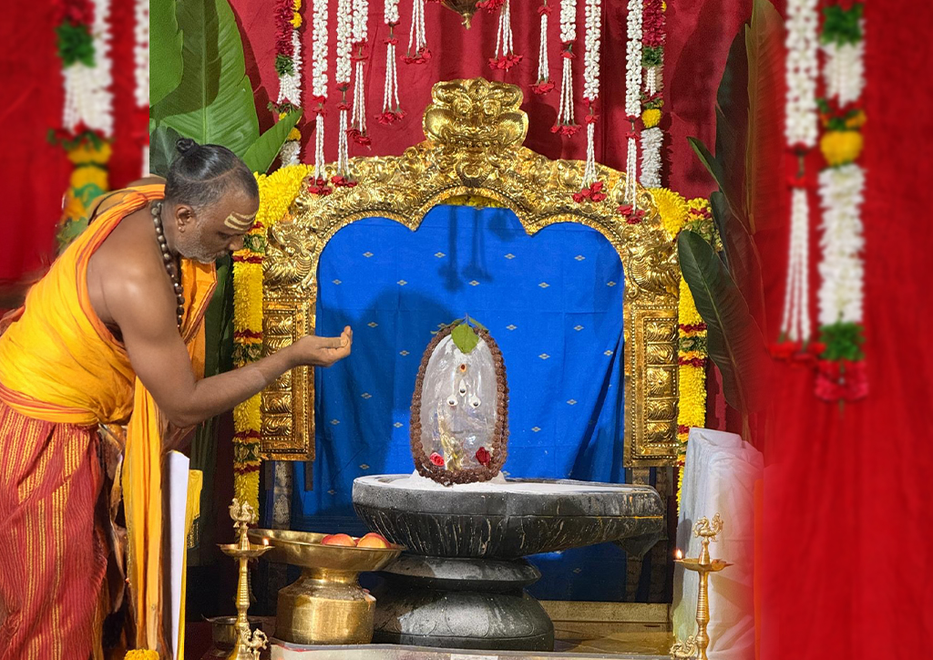 Priest offering sacred rituals to Shiva Lingam adorned with Bilva leaves and flowers at Hari Hara Kshethram.